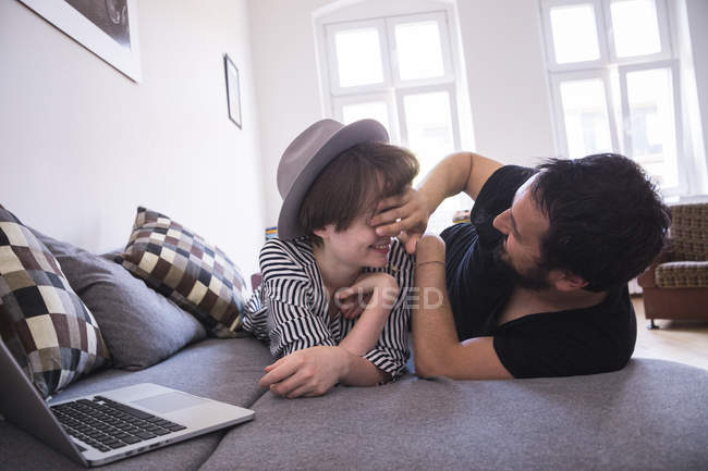 Un jeune couple diffuse des séries TV sur l'ordinateur tout en se relaxant sur le canapé dans le salon
. — Photo de stock