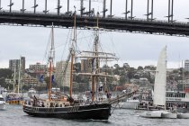 Austrália, Sydney, Navios pela ponte no porto da cidade, paisagem urbana em segundo plano — Fotografia de Stock