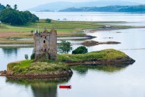 Regno Unito, Scozia, Argyll e Bute, Veduta di Castle Stalker su una piccola isola rocciosa nel lago Loch e barca rossa che passa — Foto stock