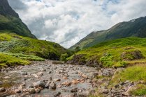 Reino Unido, Escócia, Highland, Ballachulish, Glencoe paisagem de montanhas verdes com pequeno riacho — Fotografia de Stock