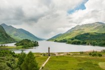 Royaume-Uni, Écosse, Highland, Glenfinnan, Le monument de Glenfinnan à distance, Glenfinnan est un petit village dans les Highlands écossais, paysage de montagnes pittoresque avec lac — Photo de stock