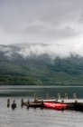 Reino Unido, Escocia, Argyll y Bute, Arrochar, Lago Lomond paisaje escénico y barco amarrado por muelle - foto de stock