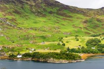 Reino Unido, Escocia, Highland, Strathcarron, Loch Carron, paisaje montañoso escénico con pueblo junto al lago - foto de stock