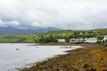 Reino Unido, Escócia, Highlands, Ilha de Skye, Carbost, Talisker Distillery, paisagem montanhosa cênica com aldeia junto ao lago — Fotografia de Stock