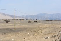 Pérou, Ica, Nasca, Nazca, Paysage déserté avec cabanes et montagnes en arrière-plan — Photo de stock