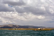 Perù, Puno, Uros, paesaggio naturale con lago e piccolo villaggio sulla riva — Foto stock