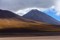 Paisaje abandonado con volcán Licancabur en la frontera entre Bolivia y Chile - foto de stock