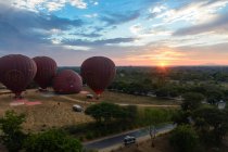 Myanmar (Burma), Mandalay region, Old Bagan, Balloons over Bagan, cars parked by field at sunshine — Stock Photo