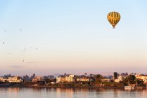 Дальний вид на дома вблизи реки и воздушный шар, Луксор, Луксор провинции, Египет — стоковое фото