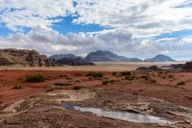 Jordania, Aqaba Gouvernement, Wadi Rum, Wadi Rum es una meseta alta del desierto en el sur de Jordania. Paisaje desértico escénico con pequeño arroyo y montañas - foto de stock