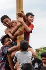 KABUL BULELENG, BALI, INDONESIA - 17 DE AGOSTO DE 2015: Adolescentes del pueblo trepan sobre un poste de madera engrasado - foto de stock
