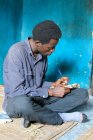 Tansania, Sansibar, Pemba-Insel, Mann sitzt und schreibt in Notizbuch — Stockfoto