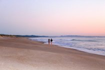 Nueva Zelanda, Isla Norte, Northland, Waipú, amanecer y pareja caminando en la playa - foto de stock