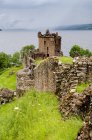 Reino Unido, Escocia, Highland, Inverness, Moray Firth, Vista de las ruinas del castillo Castillo de Urquhart en colinas verdes junto al lago - foto de stock
