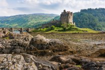 Reino Unido, Escocia, Highland, Dornie, Loch Duich, Eilean Donan Castillo con puente en el paisaje natural - foto de stock