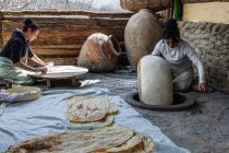 Armenia, provincia de Kotayk, mujeres pegando masa fina de oblea dentro del horno de piedra de leña - foto de stock