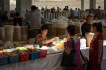 Vista de dos mujeres comprando dulces en el mercado, Samarcanda, provincia de Samarcanda, Uzbekistán - foto de stock