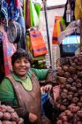 Mujer asiática vendiendo patatas en el mercado, Mercado de Arequipa,, Arequipa, Perú - foto de stock