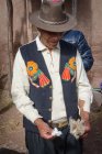 Reifer Mann in Hut und Weste mit traditioneller Stickerei bei der Herstellung von Seife, Puno, Peru — Stockfoto