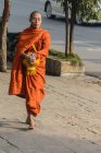 Buddhistischer Mönch in orangefarbenem Mantel, der durch die Stadtstraße geht, mandalay, mandalay region, myanmar — Stockfoto