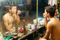 Vista del actor asiático aplicando maquillaje delante del espejo, Yogyakarta, Java, Indonesia - foto de stock