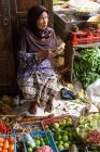 Индонезия, Ява, Джокьякарта, старшая женщина в традиционной одежде, сидящая на рынке — стоковое фото