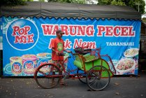 Rickshaw driver de pé perto de loja de rua, Yogyakarta, Java, Indonésia — Fotografia de Stock