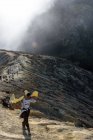 Java, Індонезії - 18 червня 2018: Сірка видобутку на вулкані Ijen, людина, несучи сірки в кошики, більш дерев'яний ящик — стокове фото