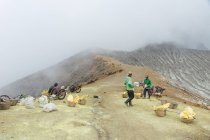 ДЖАВА, ИНДОНЕЗИЯ - 18 июня 2018 года: рабочие, перевозящие серу с вулкана Иджен — стоковое фото