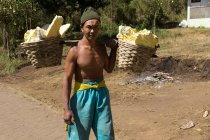 JAVA, INDONESIA - 18 DE JUNIO DE 2018: Minería de azufre en el volcán Ijen, hombre portador de azufre en canastas - foto de stock