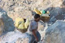 Java, Індонезії - 18 червня 2018: Сірка видобутку на вулкані Ijen, людина, несучи сірки в кошики, більш дерев'яний ящик — стокове фото