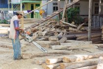 Indonesia, Sulawesi Selatan, Bulukumba, man with chainsaw near wooden boards — Stock Photo