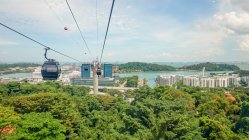 Сингапур, Сингапур, канатная дорога над зеленым побережьем с современным городским пейзажем — стоковое фото