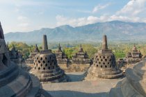 Indonesia, Java, Magelang, Buddhist temple complex of Borobudur, Stupas and mountains landscape on background — Stock Photo