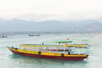 Indonésia, Nusa Tenggara Barat, Lombok Utara, Na ilha de Pulau Gili Meno, balsa e barcos em frente a uma cadeia montanhosa — Fotografia de Stock