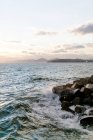 Греция, Аттика, Палео Фалиро, вечерний вид на море, город на скалистом побережье на заднем плане — стоковое фото