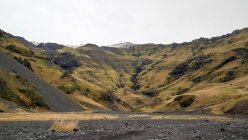 Paesaggio montuoso con cascata lontana, Islanda — Foto stock