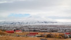 Islandia, Reikiavik, asentamiento frente a montañas nevadas en Islandia - foto de stock
