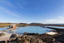 Vista lejana de las personas que se relajan en la piscina geotermal, Reikiavik, Islandia - foto de stock