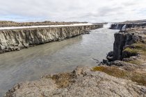 River surrounded by cliffs and distant Godafoss waterfall, Iceland — Stock Photo