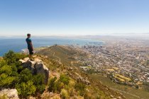 Sud Africa, Western Cape, Uomo godendo Città del Capo vista aerea da Table Mountain National Park, paesaggio urbano dalla costa dell'oceano al sole — Foto stock