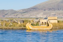 Перу, Пуно, Пуно, озеро Тітікака, традиційні човен пришвартований на пірсі, на фоні гори — стокове фото