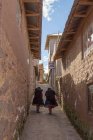 Perú, Puno, Puno, vista de dos mujeres caminando por el callejón - foto de stock