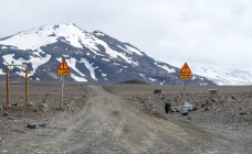 Segnali stradali di avvertimento sulla strada sterrata e sul lontano ghiacciaio Langjokull, Islanda — Foto stock