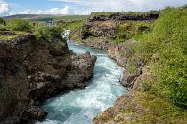 Vista distante de turistas em falésias por rio, Islândia — Fotografia de Stock