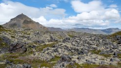 Costa di basalto frastagliata sotto il cielo blu nuvoloso, Islanda — Foto stock