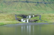 Islandia, Snefellsnes, paisaje escénico con Kirkjufellsfoss Cascada junto al lago de montaña - foto de stock