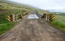 Camino de tierra con pequeño puente y lejano paisaje brumoso, Islandia — Stock Photo