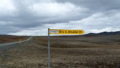Ісландська порожній краєвид з дороги і стрілами підписати на передньому плані — стокове фото