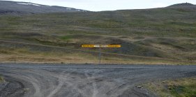 Indicazioni stradali su strada sterrata con colline sullo sfondo, Islanda — Foto stock